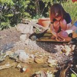 child in the garden helping build a pond by adding plants