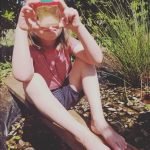 child looking into a pot of water, studying wildlife pond in the garden